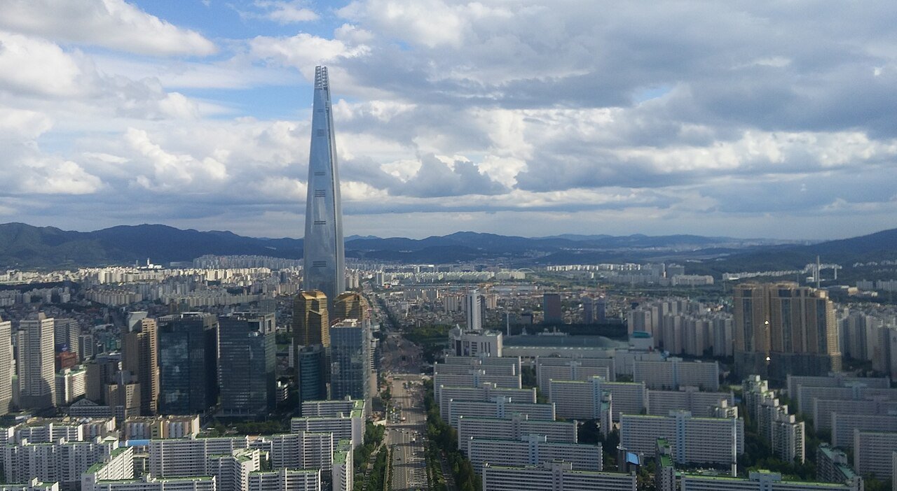 首尔壮阔的航拍全景,乐天世界塔在戏剧化的云层下耸立于城市天际线之上