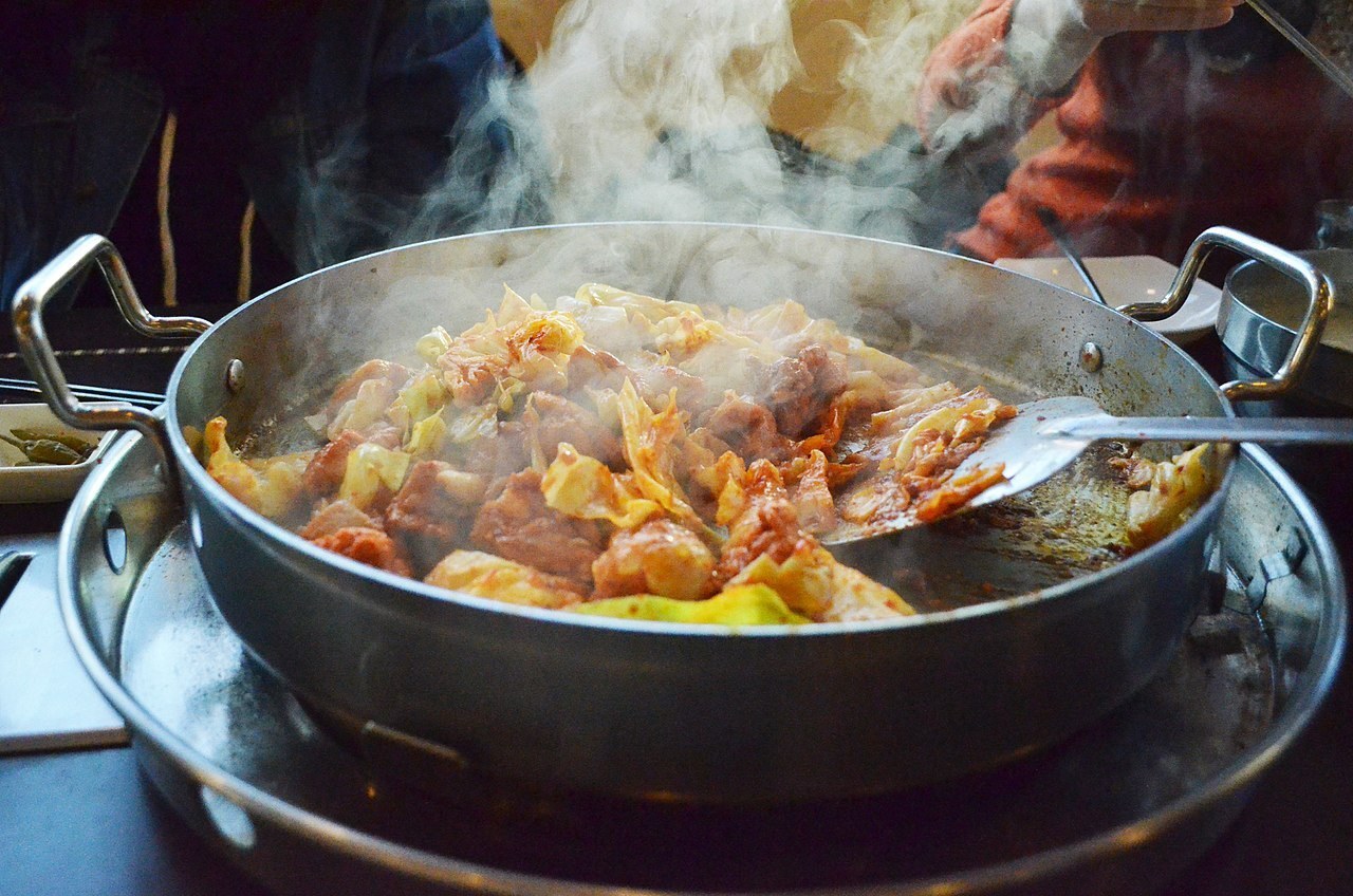 A pan of Chuncheon dakgalbi — spicy stir-fried chicken with cabbage — steaming on a tabletop burner