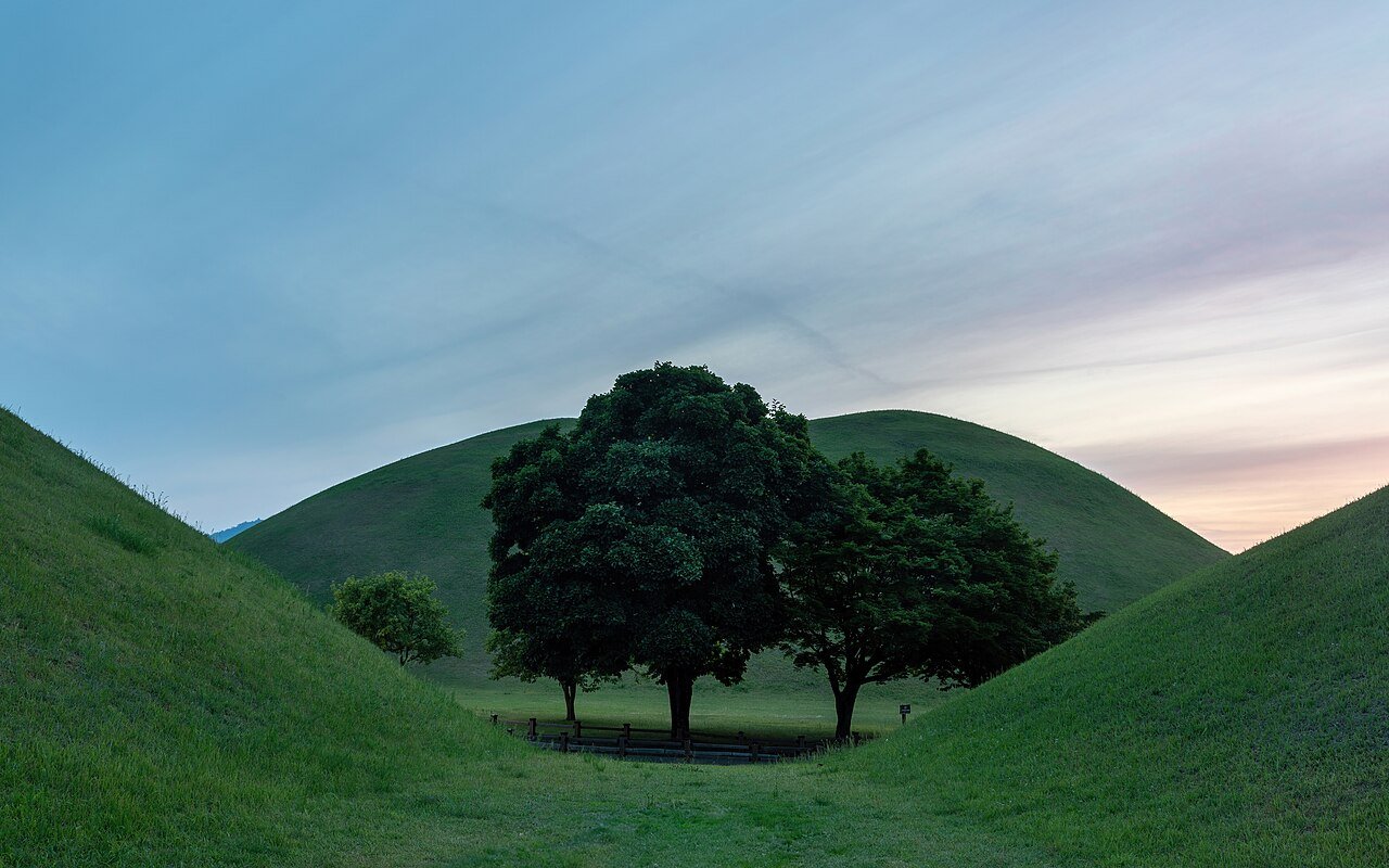 夕阳下长满青草、树木环绕的王陵土丘(大陵苑)